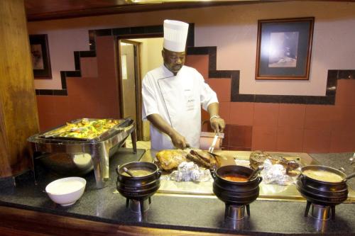 a chef preparing food in a restaurant kitchen at Cresta Mowana Safari Resort & Spa in Kasane