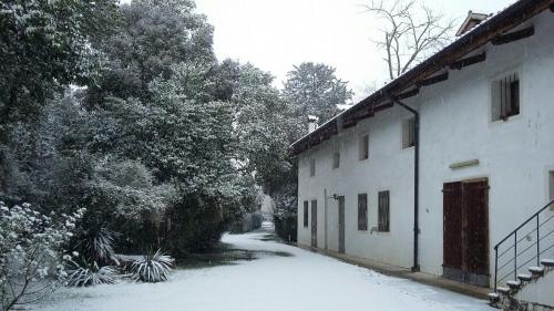 a snow covered alley next to a building with trees at Villa Mainardi Agriturismo in Camino al Tagliamento