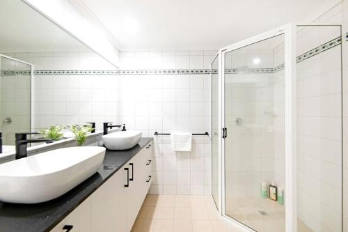 a white bathroom with two sinks and a shower at Sunset Penthouse - Unique Panoramic Rooftop Retreat in Larrakeyah
