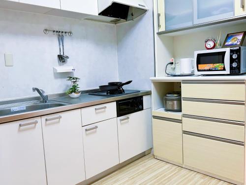 a kitchen with white cabinets and a sink and a microwave at yikebukuro LuckyHouse 池袋一軒家 幸運の家 in Tokyo