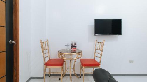 a small table with two chairs and a tv on a wall at RedDoorz @ St. Catherine Residences Olongapo City in Olongapo
