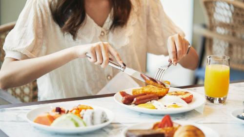 a woman cutting a plate of breakfast food at Hyatt Regency Guangzhou Zengcheng in Guangzhou