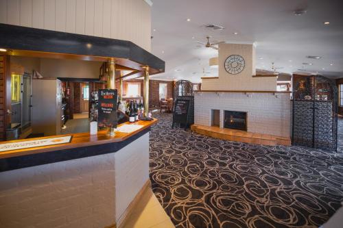 a restaurant with a fireplace and a bar in the middle at Country Club Villas in Launceston