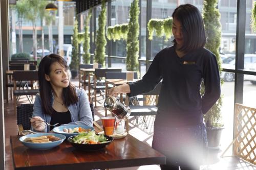 a woman pouring a woman a glass of wine at a table at Cmor by Recall Hotels SHA Extra Plus in Chiang Mai