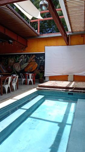 a swimming pool with a table and chairs and a screen at La Esmeralda Oaxaca in Oaxaca City