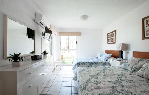 a bedroom with a bed and a couch and a tv at Marina Suites by Andiani Travel in Bucerías