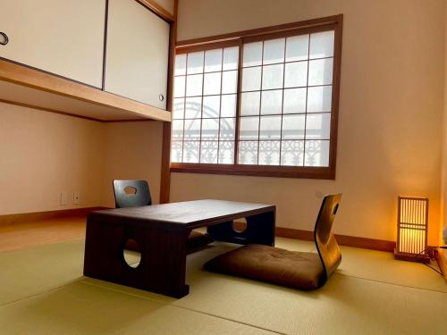 a table and a chair in a room with a window at 伊東山荘-Toki- in Ito
