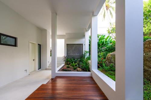 an open hallway with white walls and wood floors at Anzhu Seamate Villa Samui in Amphoe Koh Samui