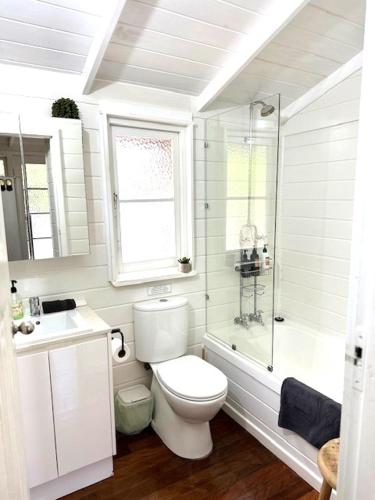 a white bathroom with a toilet and a shower at Hidden Gem, Megalong Valley, Blue Mountains in Kanimbla