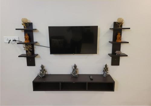 a tv hanging on a wall with shelves at Tapovan Rishikesh Luxury Blessing Stay in Rishīkesh