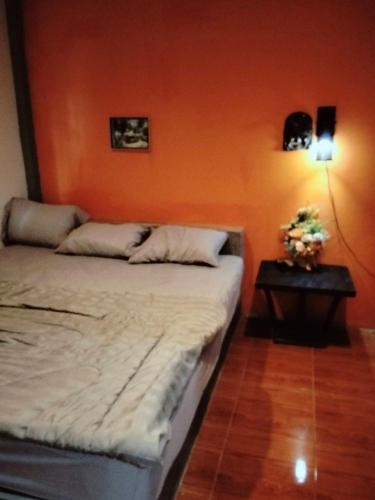 a bed in a room with an orange wall at ณชนกรีสอร์ท in Ban Maha Chai