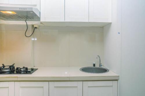 a white kitchen with a sink and a stove at Minimalist and Comfy Studio at Grand Dhika City Apartment By Travelio in Bekasi