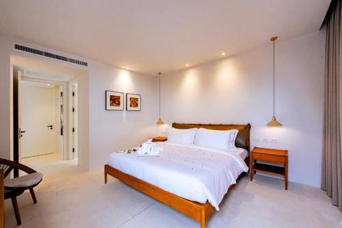 a bedroom with a large white bed and a chair at Anzhu Seamate Villa Samui in Amphoe Koh Samui