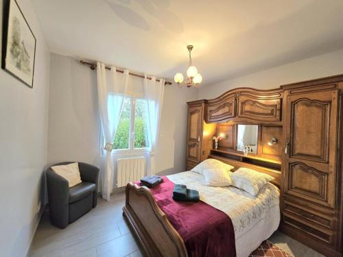 ein Schlafzimmer mit einem großen Holzbett und einem Stuhl in der Unterkunft Belle maison plain-pied à 2 pas de Périgueux, terrasse, jardin clos, confort moderne, animaux bienvenus - FR-1-616-99 in Champcevinel