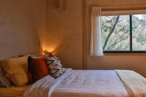 a bedroom with a large bed with a window at Casa Awänímä - Luxury Permaculture Hotel & Eco-Retreat in Tzununá