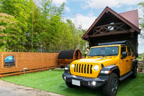 a yellow jeep parked in front of a wooden building at SUGI BASE Biwako in Otsu