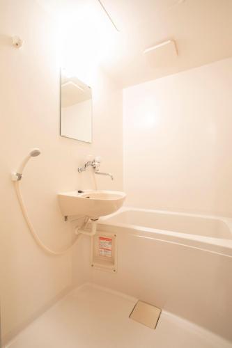 a white bathroom with a sink and a bath tub at SUGI BASE Biwako in Otsu