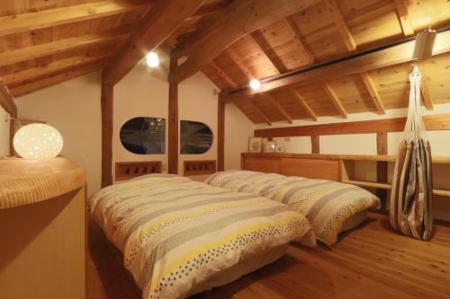 Dos camas en una habitación con techos de madera. en 十六夜山荘, en Nara