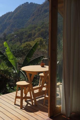 a wooden table and chairs on a deck with a mountain at Casa Awänímä - Luxury Permaculture Hotel & Eco-Retreat in Tzununá