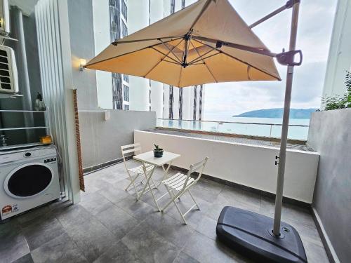 a patio with a table and an umbrella on a balcony at Seaside Pool View Studio Apartment at Kota Kinabalu City Centre in Kota Kinabalu