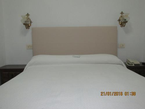 a white bed in a bedroom with two lights at Hotel Conde in Taboadela