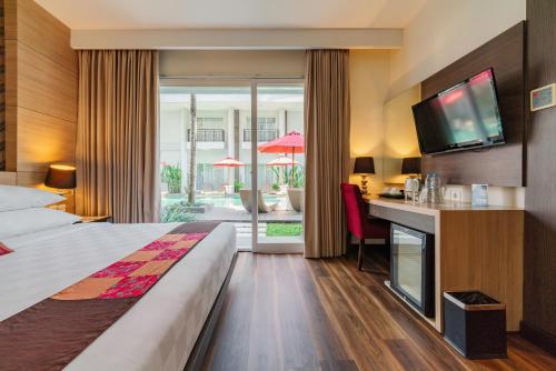 a hotel room with a bed and a desk with a television at b Hotel Bali & Spa in Denpasar