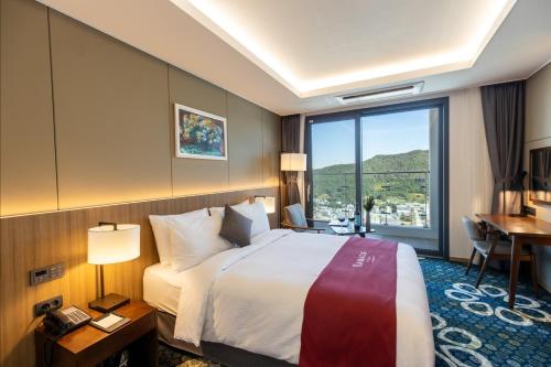 a hotel room with a bed and a large window at Ramada Plaza by Wyndham Dolsan Yeosu in Yeosu