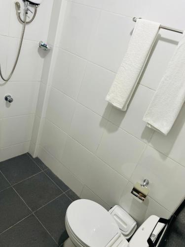 a white bathroom with a toilet and a shower at GJES Lodge AND GUESTHOUSE in Moalboal