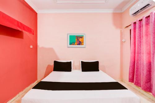 a bedroom with a white bed with red walls at Hotel O Abhilasha in Bhilai