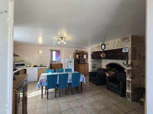 une cuisine et une salle à manger avec une table et des chaises bleues dans l'établissement Gîte familial avec cheminée, ping-pong, près de la Grotte de Tourtoirac et du Château de Hautefort - FR-1-616-8, à Tourtoirac