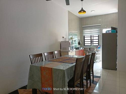 a kitchen with a table with chairs and a refrigerator at Nur Homestay bersih dan tenang in Kampong Piangu