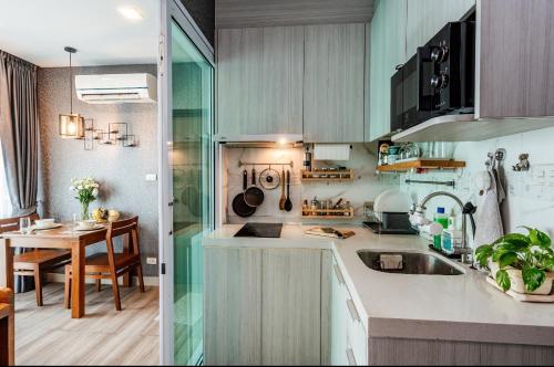 a kitchen with a sink and a table in a room at Stay with Pano at The Prio Condo in Chiang Mai