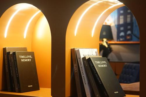 a row of books sitting on a book shelf at Arthur Hotel Liwan COCO Park Dongsha Metro Guangzhou-24H Coffee & Low Tea & Free Shuttle Bus For Canton Fair By Paco in Guangzhou
