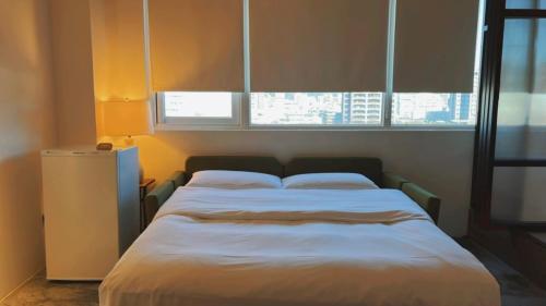 a large bed in a room with two windows at Chill Roof Hotel in Taipei