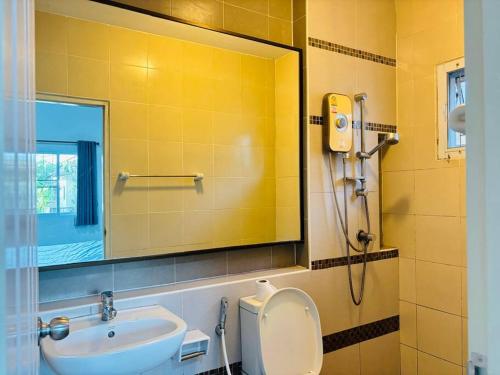 a bathroom with a sink and a toilet and a mirror at บ้านม่วนใจ๋ดีญ่า in Ban Pa Lan