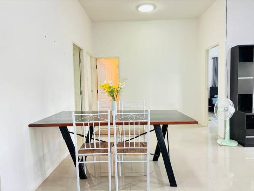 a dining room table with a vase of flowers on it at บ้านม่วนใจ๋ดีญ่า in Ban Pa Lan