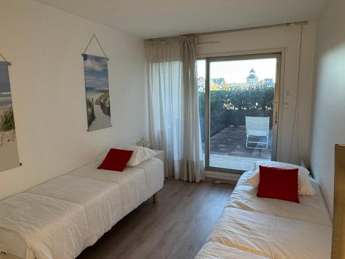 une chambre avec deux lits et un balcon avec vue dans l'établissement Appartement 3 pièces avec accès direct plage et WiFi - FR-1-487-377, à Cabourg