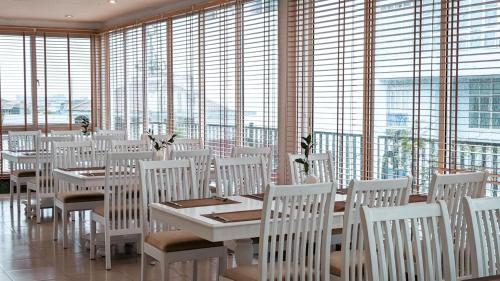 a dining room with white tables and chairs and windows at Alba Hotel in Hue