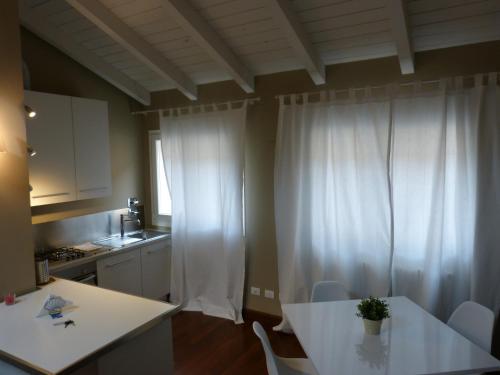 a kitchen with white curtains and a white table and chairs at Residenza Porta D'Azeglio in Bologna