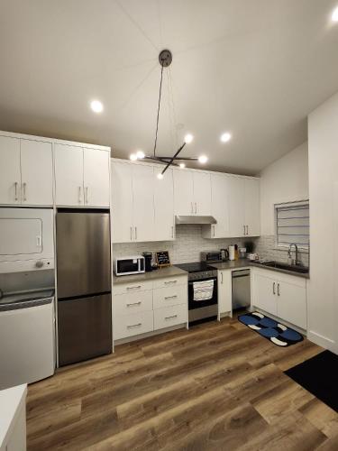 a kitchen with white cabinets and stainless steel appliances at 2BR Detached Guesthouse - Free Parking -10 mins to YVR & Downtown in Vancouver