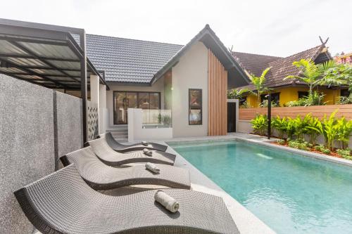 a swimming pool with chaise lounge chairs next to a house at Hey Lanna - Chic 3-Bedroom Oasis with Pool! in Chiang Mai