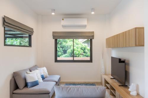 a living room with a couch and a tv at Hey Lanna - Chic 3-Bedroom Oasis with Pool! in Chiang Mai