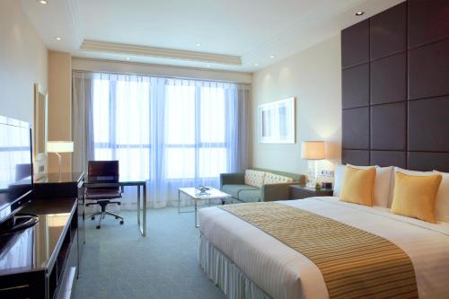 a hotel room with a large bed and a desk at Courtyard by Marriott Kunshan in Kunshan