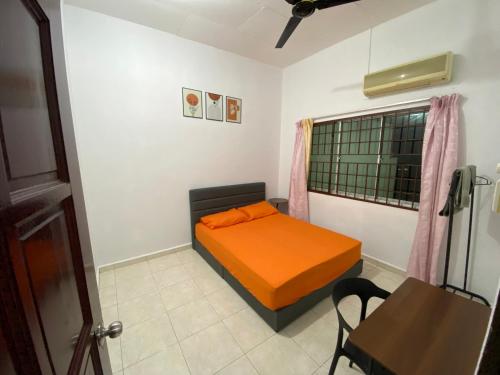 a small bedroom with an orange bed and a table at Pagoh Town homestay 2 in Pagoh
