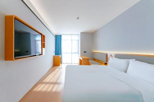 a hotel room with a bed and a flat screen tv at 南京南站咖居精选酒店 in Nanjing