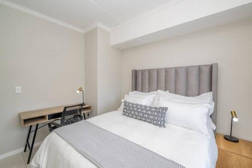 ein Schlafzimmer mit einem großen Bett mit Schreibtisch und einem Schreibtisch in der Unterkunft Cozy Apartment in Brackenfell, Cape Town, ZA in Brackenfell