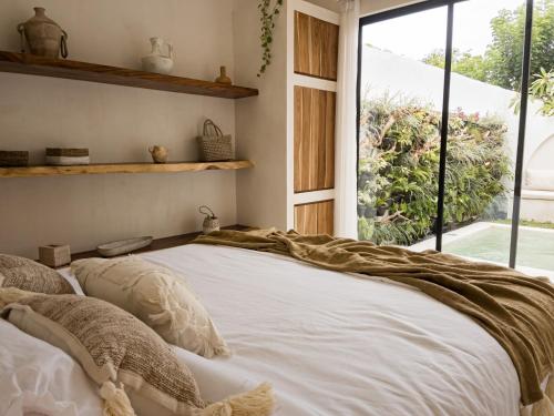 a bedroom with a large bed with pillows and a window at Bali Escapes- Studio And 1 Bedroom Villa in Uluwatu