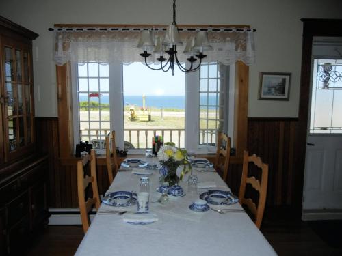 ein Esszimmer mit einem Tisch und Meerblick in der Unterkunft The Yellow Sidecar B&B in Cap Le Moine