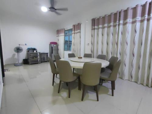 a dining room with a white table and chairs at Homezstay Swallow Airport Miri in Miri