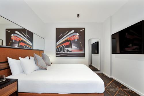 a bedroom with a large white bed and paintings on the wall at Hoteloco in Sydney